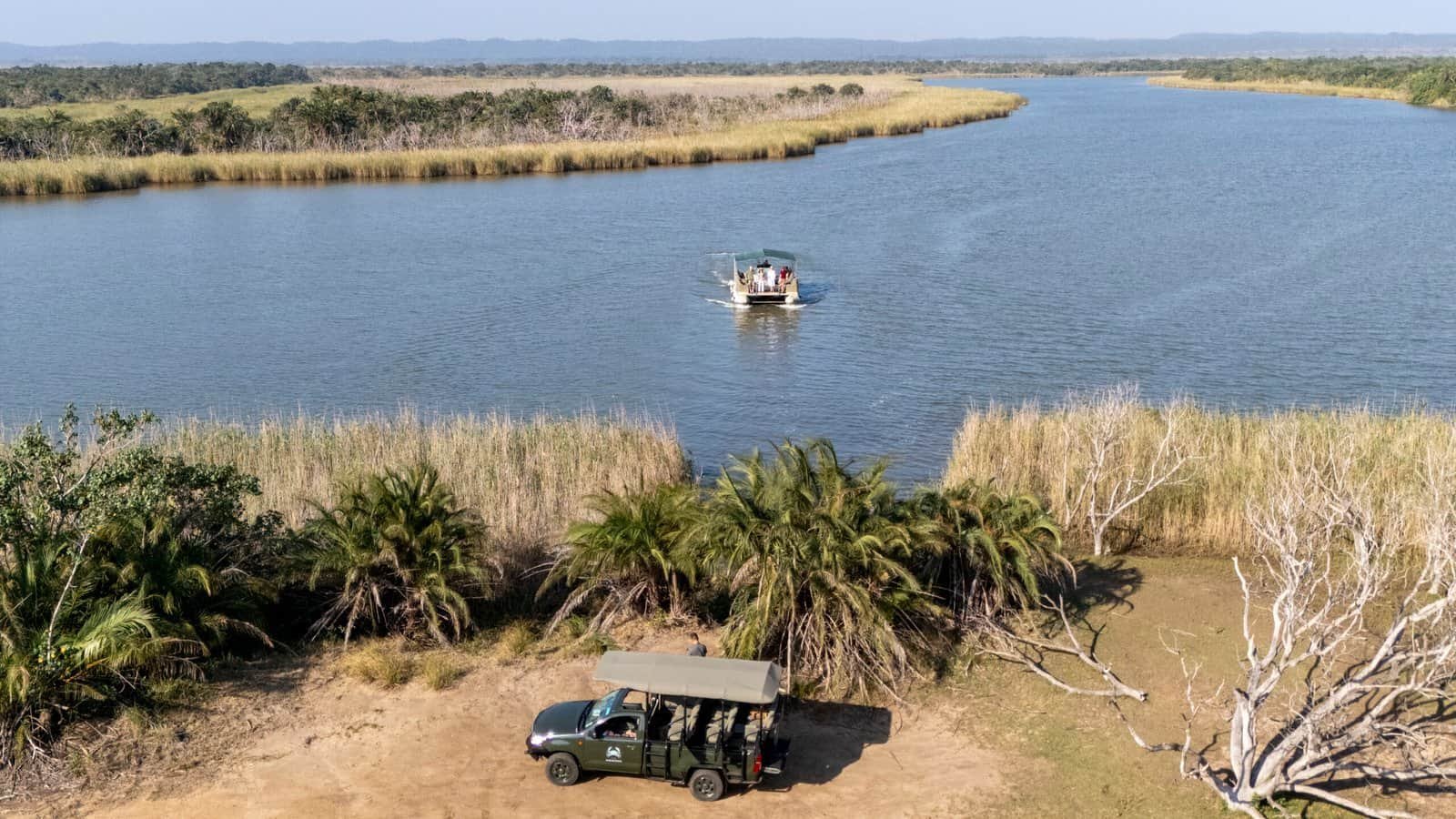 game vehicle parked in front of lake with boat floating on it