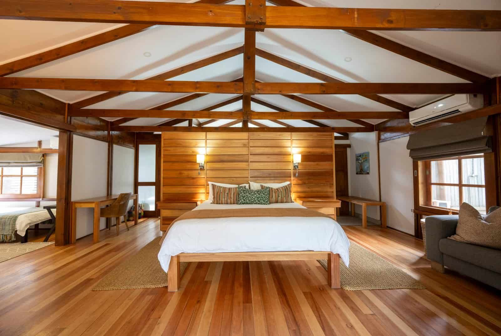 double bed in large room with couch, wooden floors