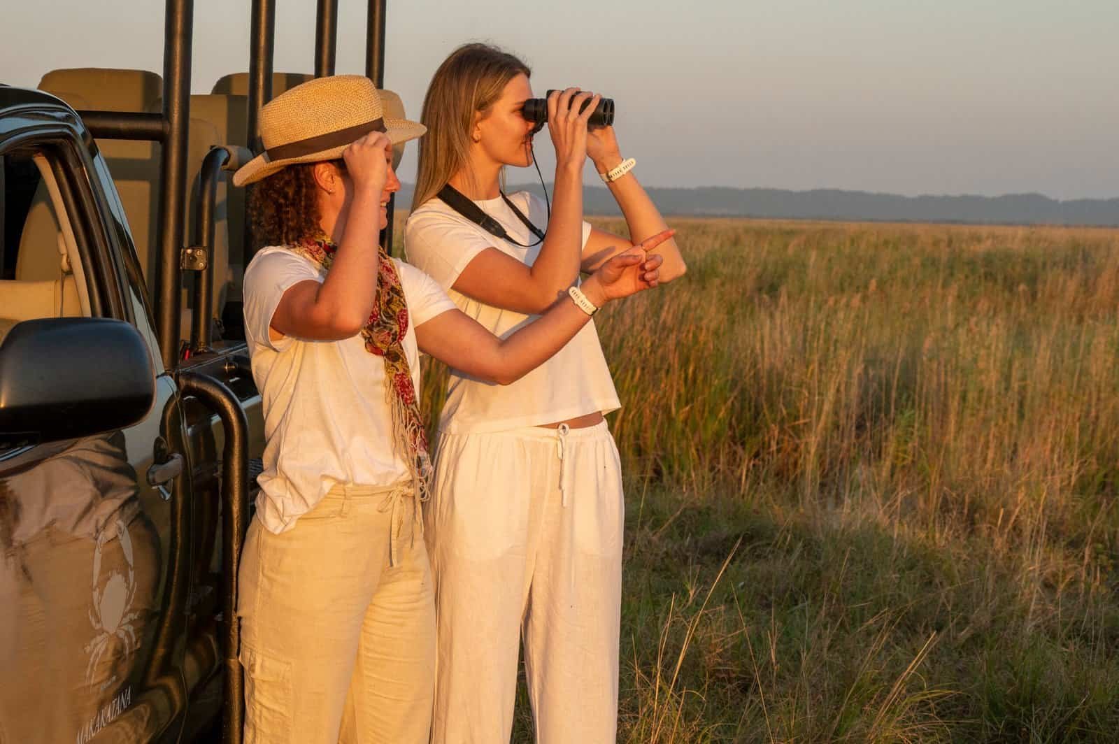 ladies looking through binoculars in front of game vehicle